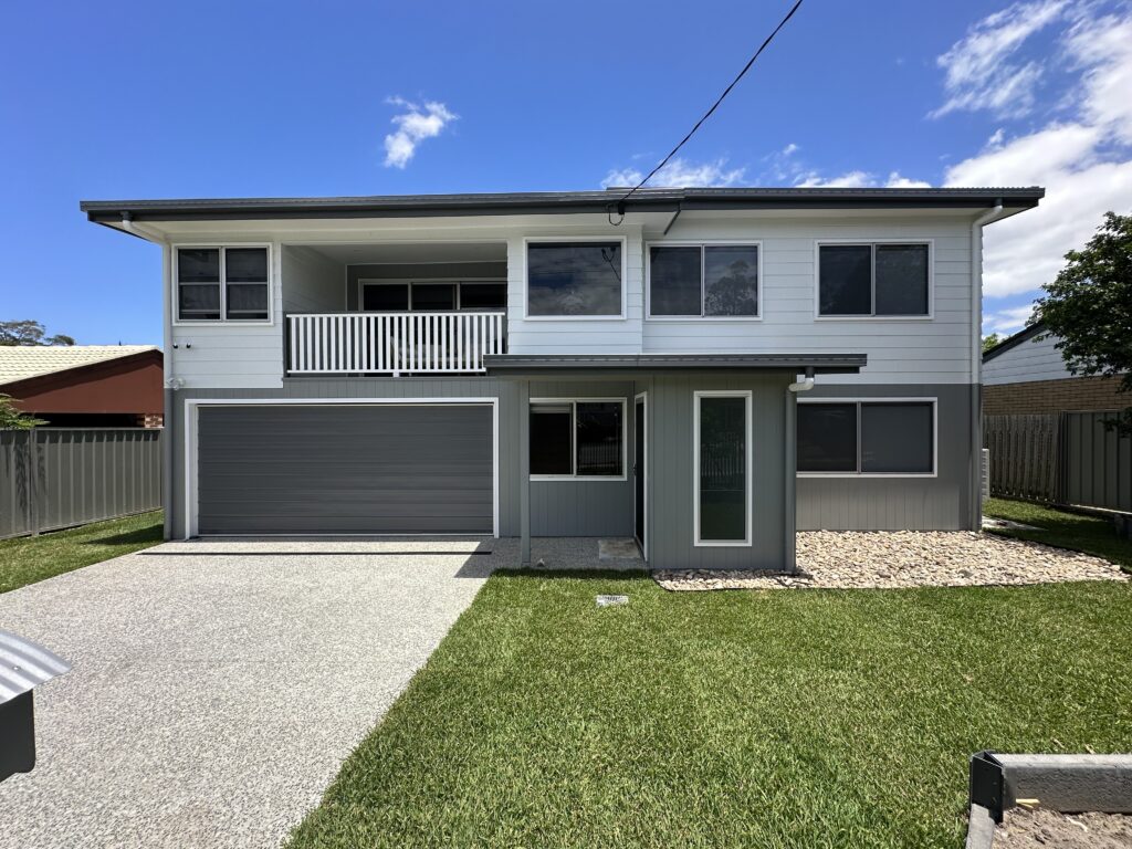 A home freshly painted white and grey with a green lawn in front